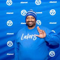 Gentleman giving Anchor Up sign in front of GV Alumni backdrop